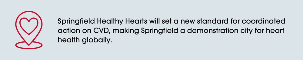 Red heart icon inside a map pin symbol on the left. To the right, text reads: 'Springfield Healthy Hearts will set a new standard for coordinated action on CVD, making Springfield a demonstration city for heart health globally.'