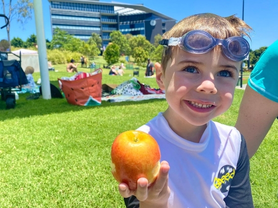 A young boy eating an apple at the pool