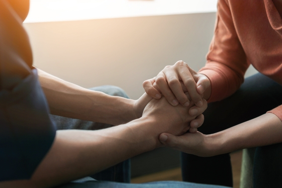 A couple sitting on a couch, holding hands affectionately.