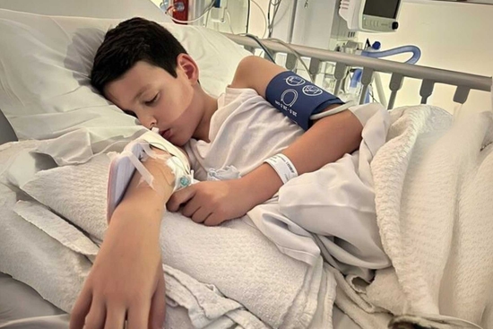 Young George who suffered a sudden cardiac arrest, lying in hospital bed 