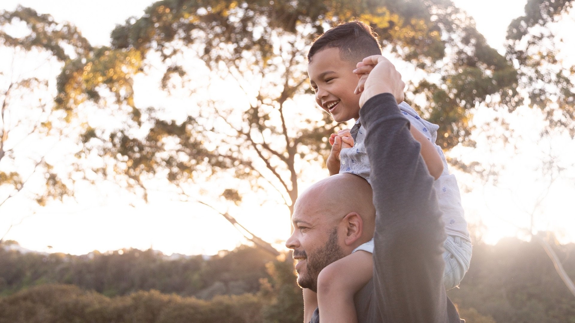 A man holding his smiling son up on his shoulders