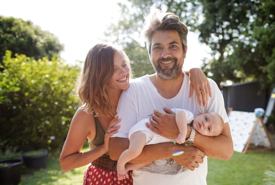 A young family standing in a backyard
