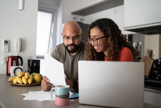 A couple sitting at the kitchen table with a laptop and documents