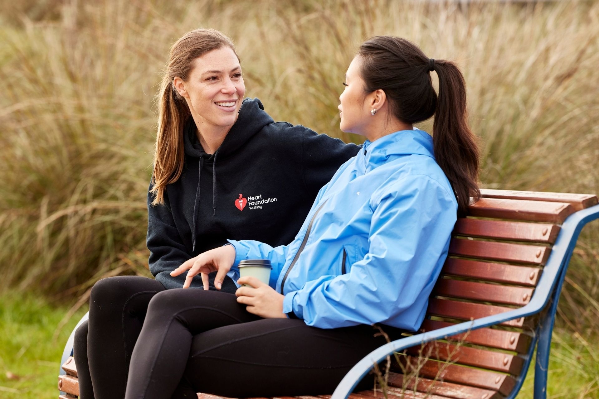Two women sitting on a park bench and talking through their heart health experiences.