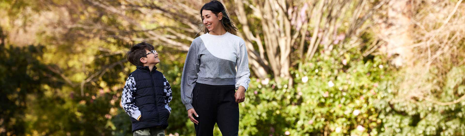 Mother and son smiling and walking through a park