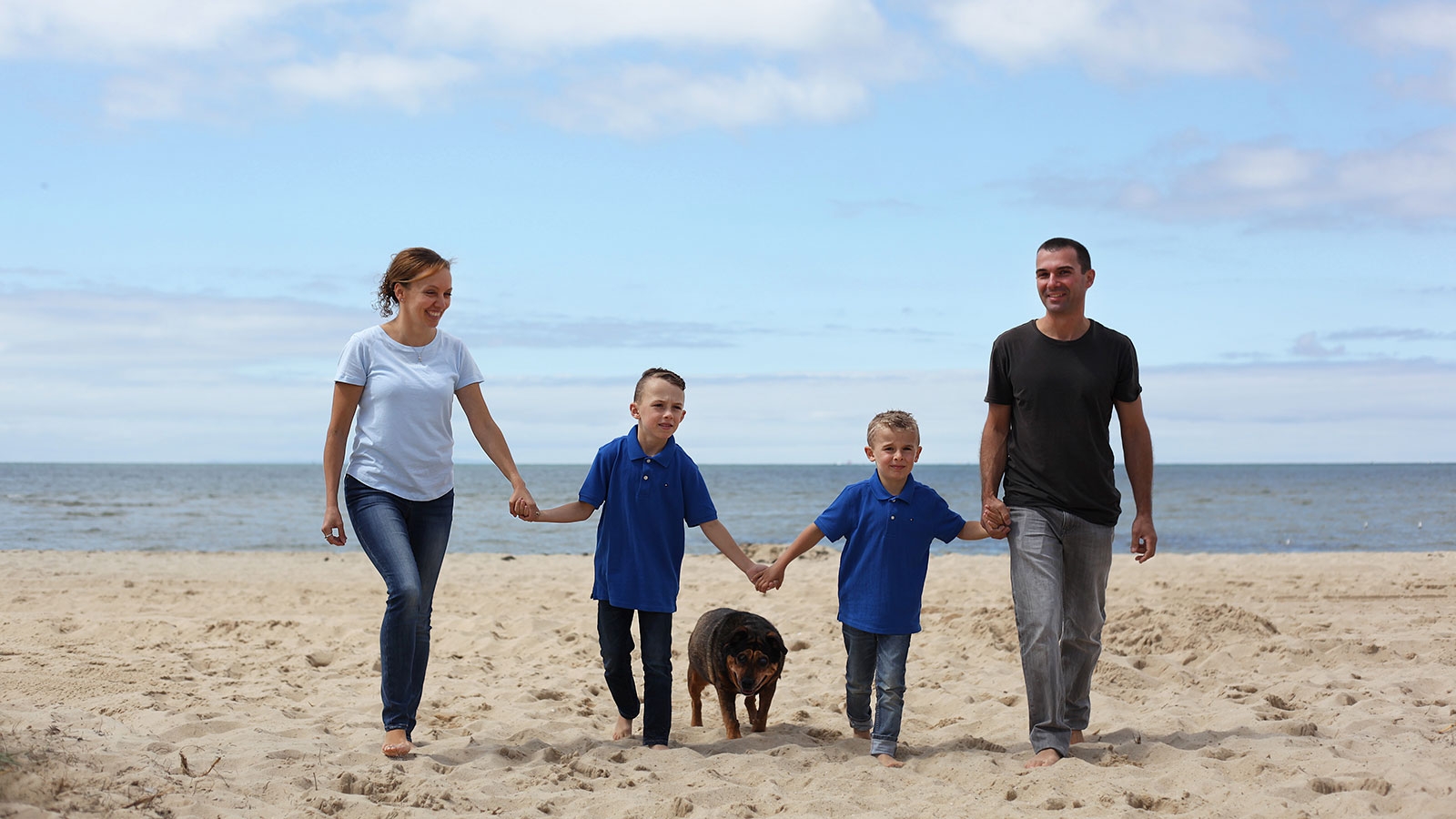 A family walking on the beach, holding hands, enjoying a peaceful and bonding moment together.