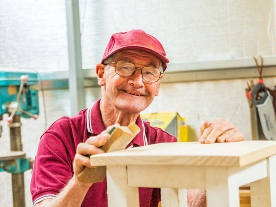 Older man at a workshop smiling at the camera