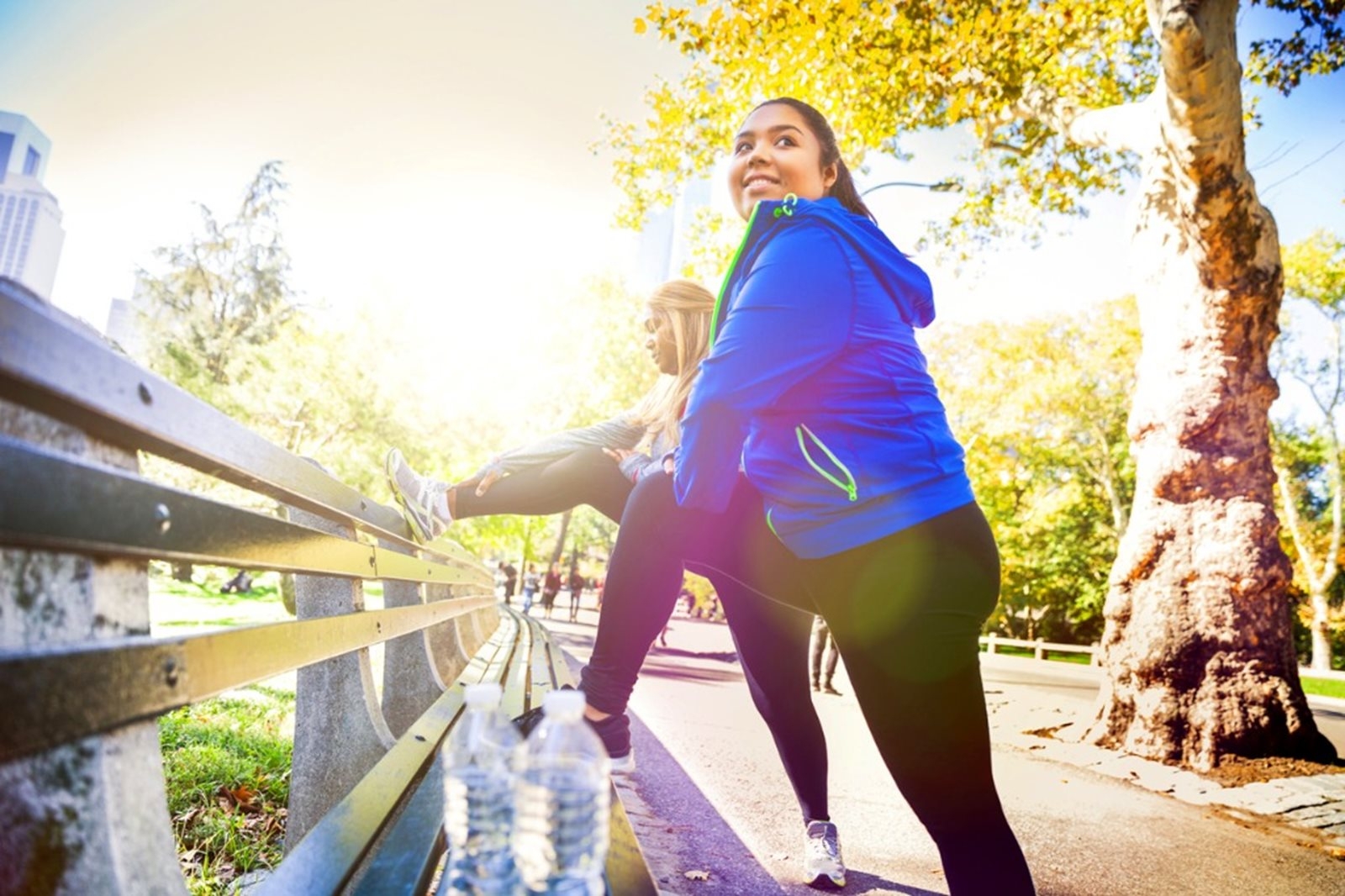 Two women stretching on a park bench, promoting physical fitness and relaxation.