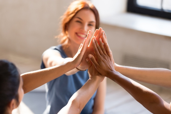 A group of women enthusiastically celebrating their success with a high five gesture.